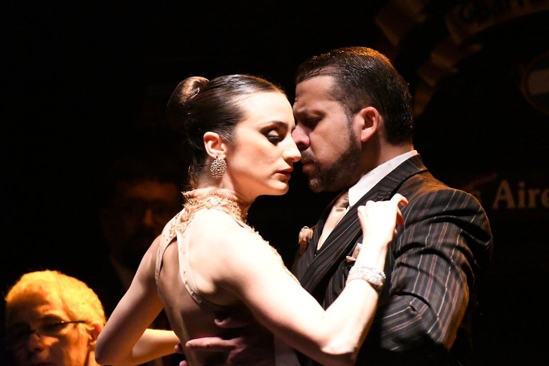 Tango-echtpaar danst dicht bij elkaar op een donker podium