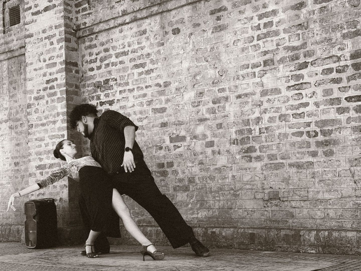 Tweepaar danst tango in close embrace tegen een bakstenen muur
