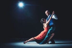 Tango-danspaar voert een lage, gestrekte beweging uit onder spotlicht